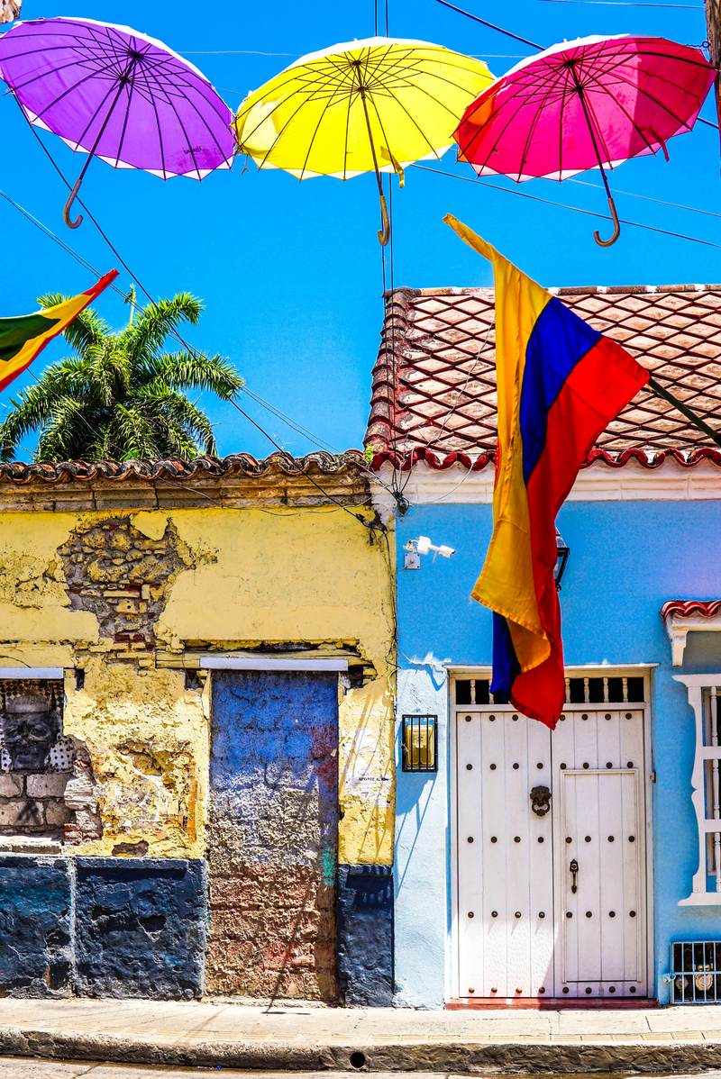 Colourful umbrellas and a Colombian flag above a street in Cartagena