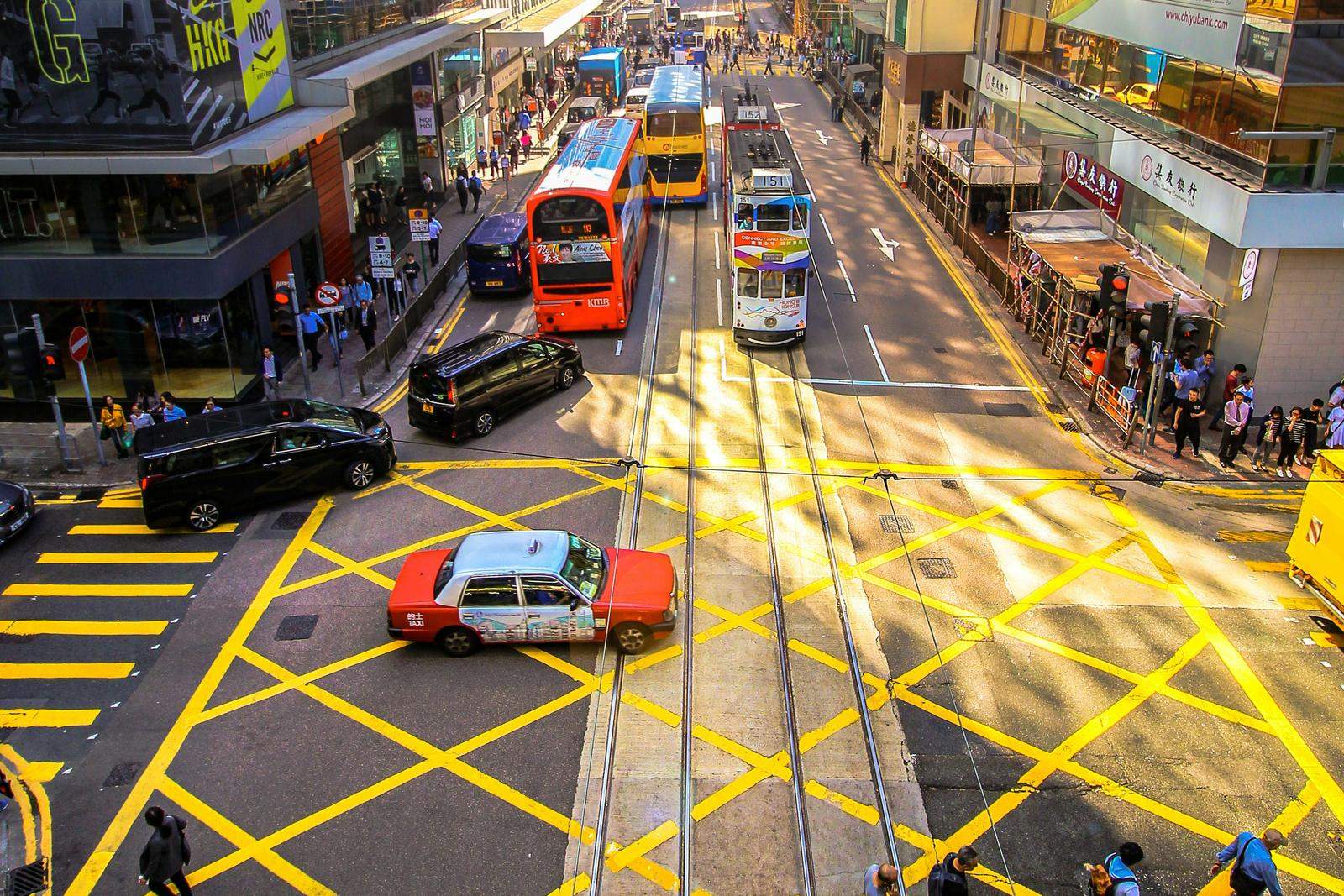 Trams, buses and a red taxi on a busy street in Central, Hong Kong