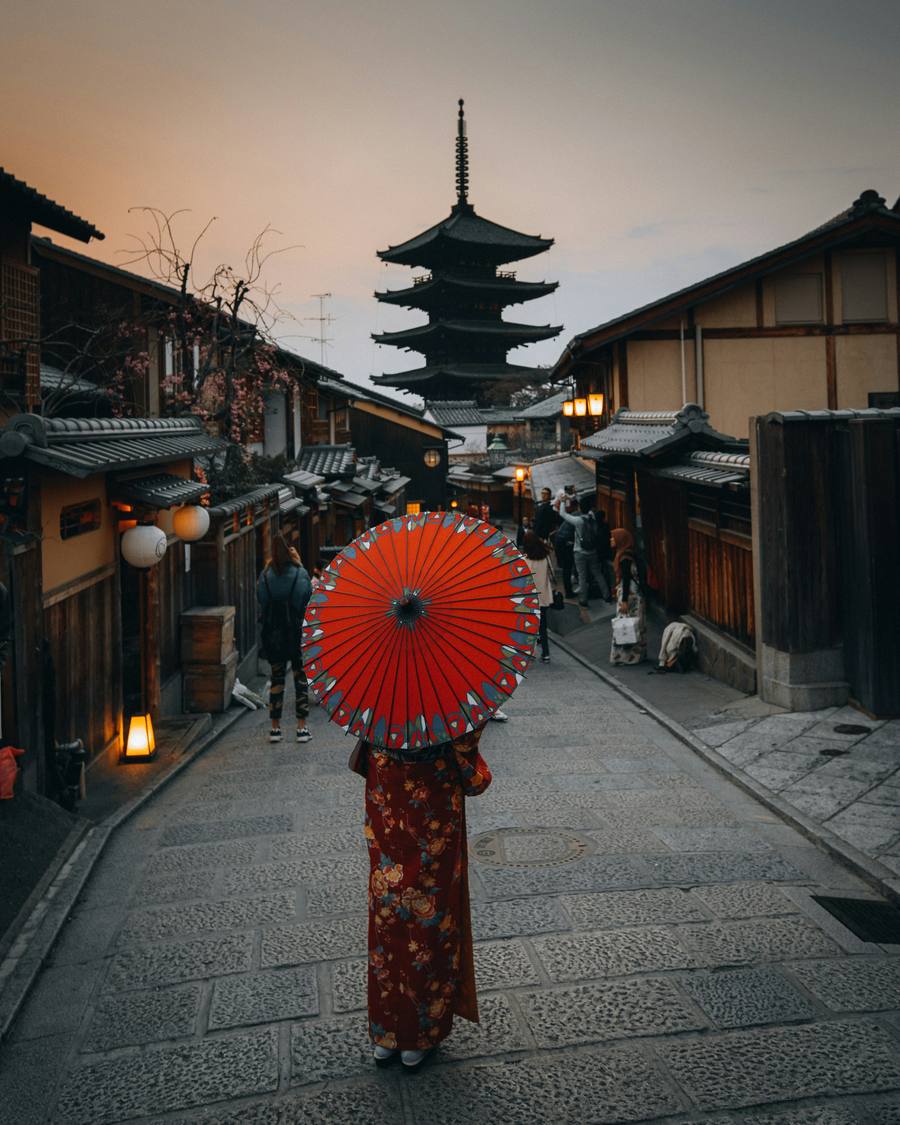 Woman in a kimono with a red umbrella below Yasaka Pagoda in Kyoto