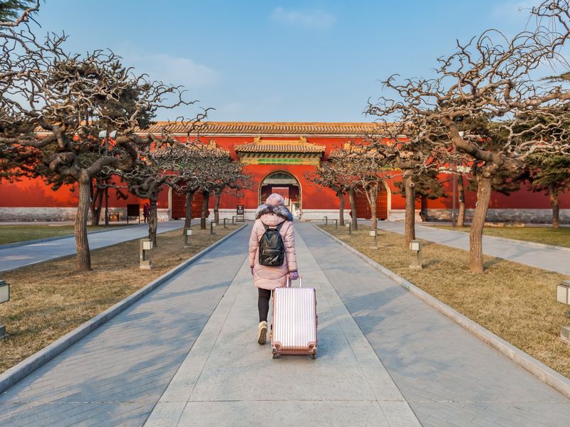 New teacher with a suitcase arriving at a palace gate in Beijing